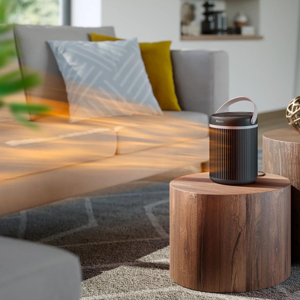 Chauffage Philips CX3120 posé au sol dans un salon chaleureux, près d'un canapé et d'un plaid