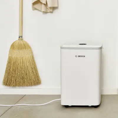 Déshumidificateur Bosch Dry 2000 en mode séchage du linge à côté d'un étendoir chargé de vêtements
